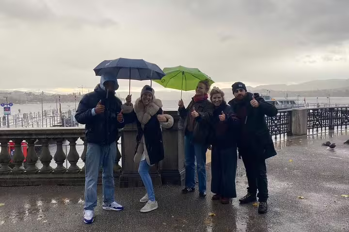 Friends on rainy Lake Zurich promenade during Zurich scavenger hunt self-guided tour, thumbs up