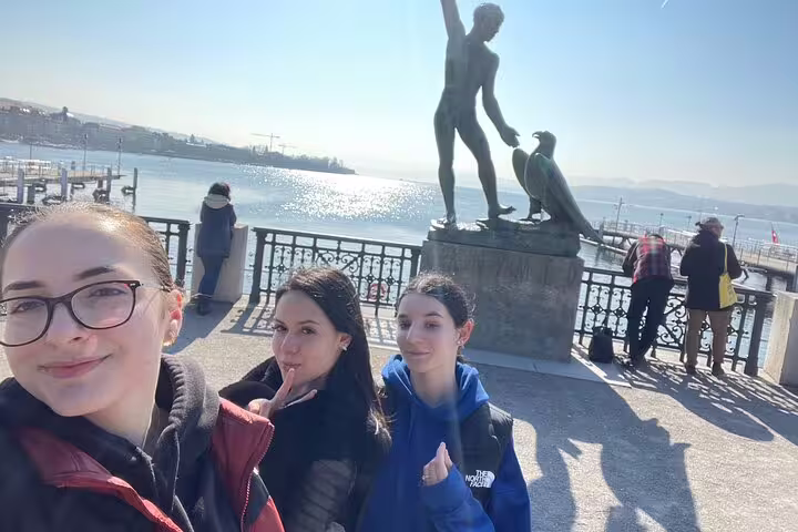 Travelers at Lake Zurich promenade near Ganymed statue during a Zurich scavenger hunt and sights tour