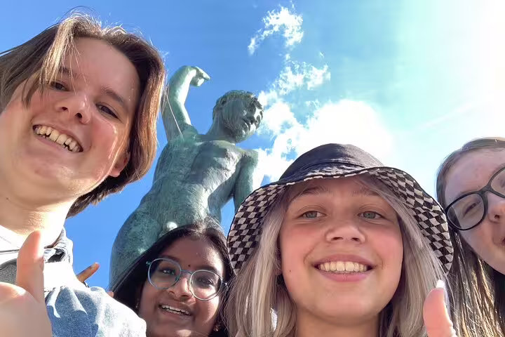 Friends selfie by Zurich statue on a self-guided scavenger hunt tour, exploring city sights in Switzerland