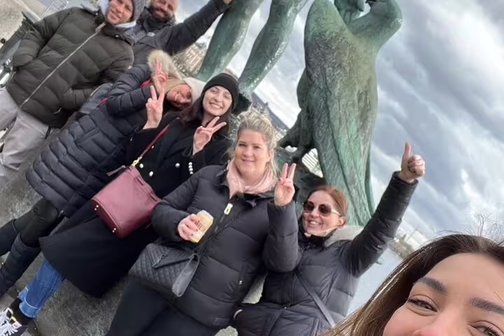 Group selfie by Zurich statue on a self-guided scavenger hunt and sights tour, winter city views