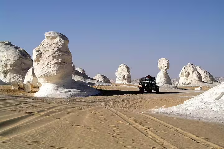 4x4 jeep driving among White Desert chalk formations on Bahariya Oasis overnight camping and desert safari
