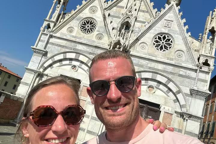 Happy couple smiling in front of Pisa cathedral during a self-guided mystery puzzle adventure tour