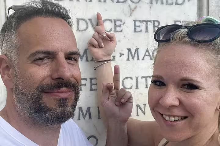 Couple decoding clues on a Latin inscription during Pisa self-guided mystery puzzle walking tour