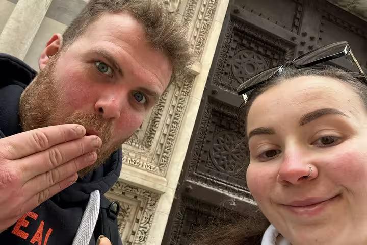 Couple taking fun selfie at ornate Pisa cathedral doorway during self-guided mystery puzzle adventure tour
