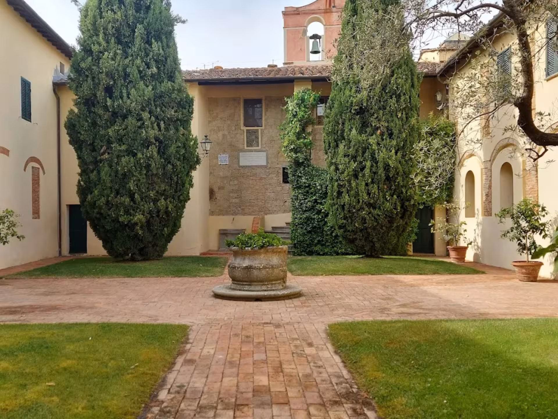 Charming courtyard of a historic abbey surrounded by lush greenery near Pisa, Tuscany.