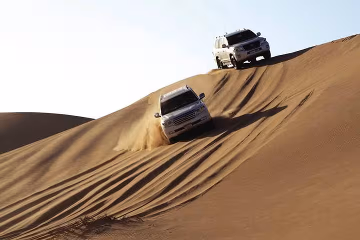 Experience thrilling desert safari in Abu Dhabi with SUVs navigating sandy dunes under the clear blue sky.