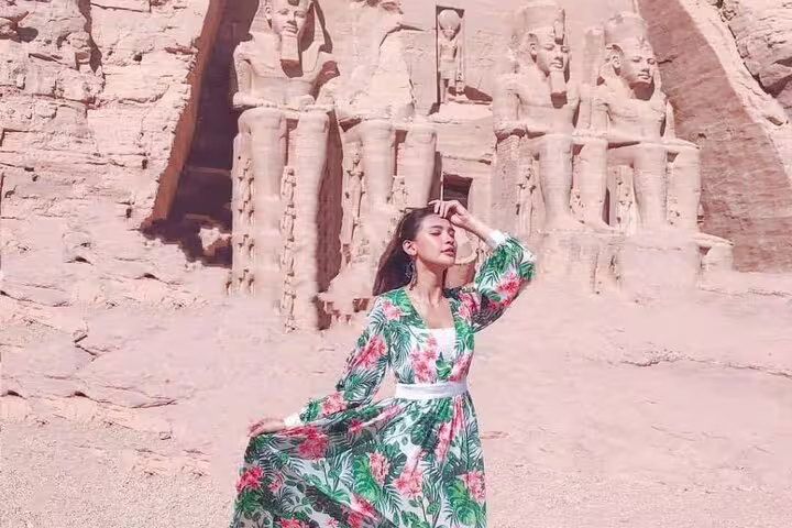 Traveler posing by the Abu Simbel Great Temple statues during a day trip from Aswan in southern Egypt