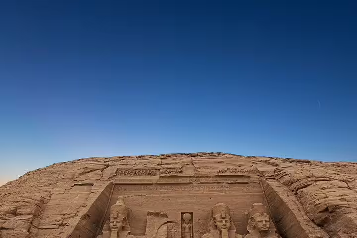 Wide view of Abu Simbel Great Temple facade under blue sky, highlight of a day tour from Aswan