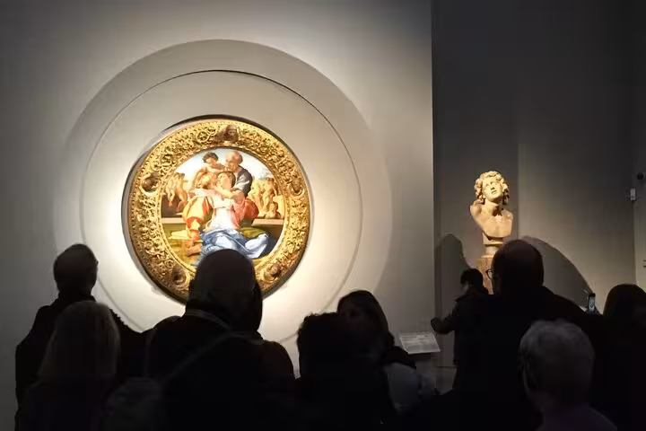 Tourists explore Michelangelo's 'Doni Tondo' at Uffizi Gallery, featured in the Accademia & Uffizi private tour.