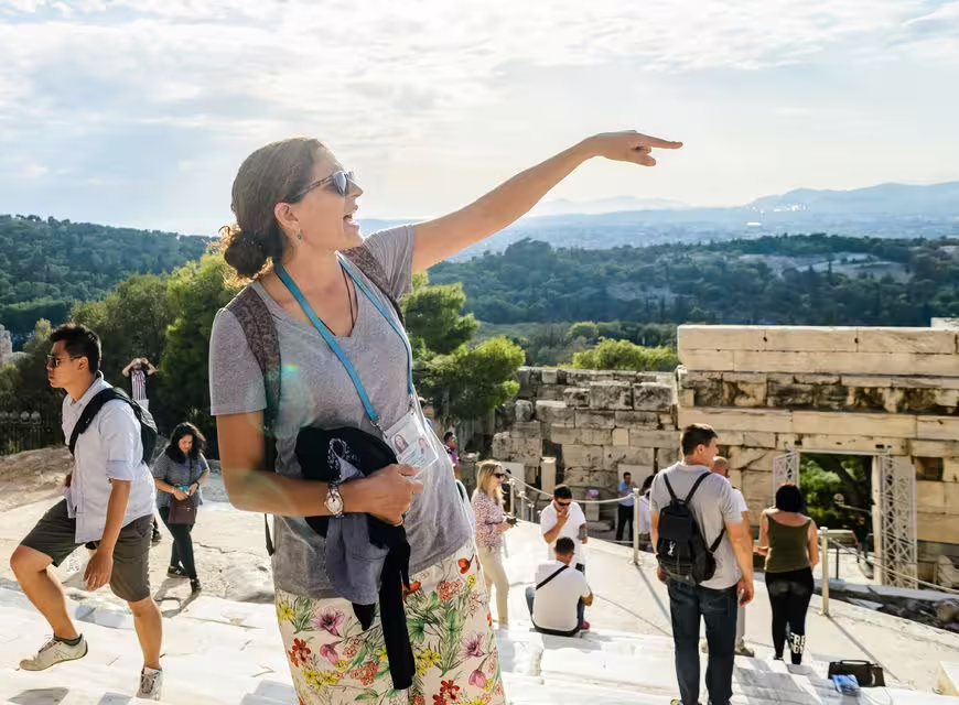 Licensed guide pointing out landmarks during Acropolis Morning tour with Parthenon ruins behind