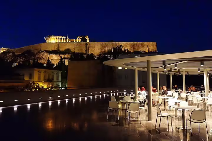 Outdoor dinner terrace with Acropolis and Parthenon lit at night, optional dining on Friday night tour