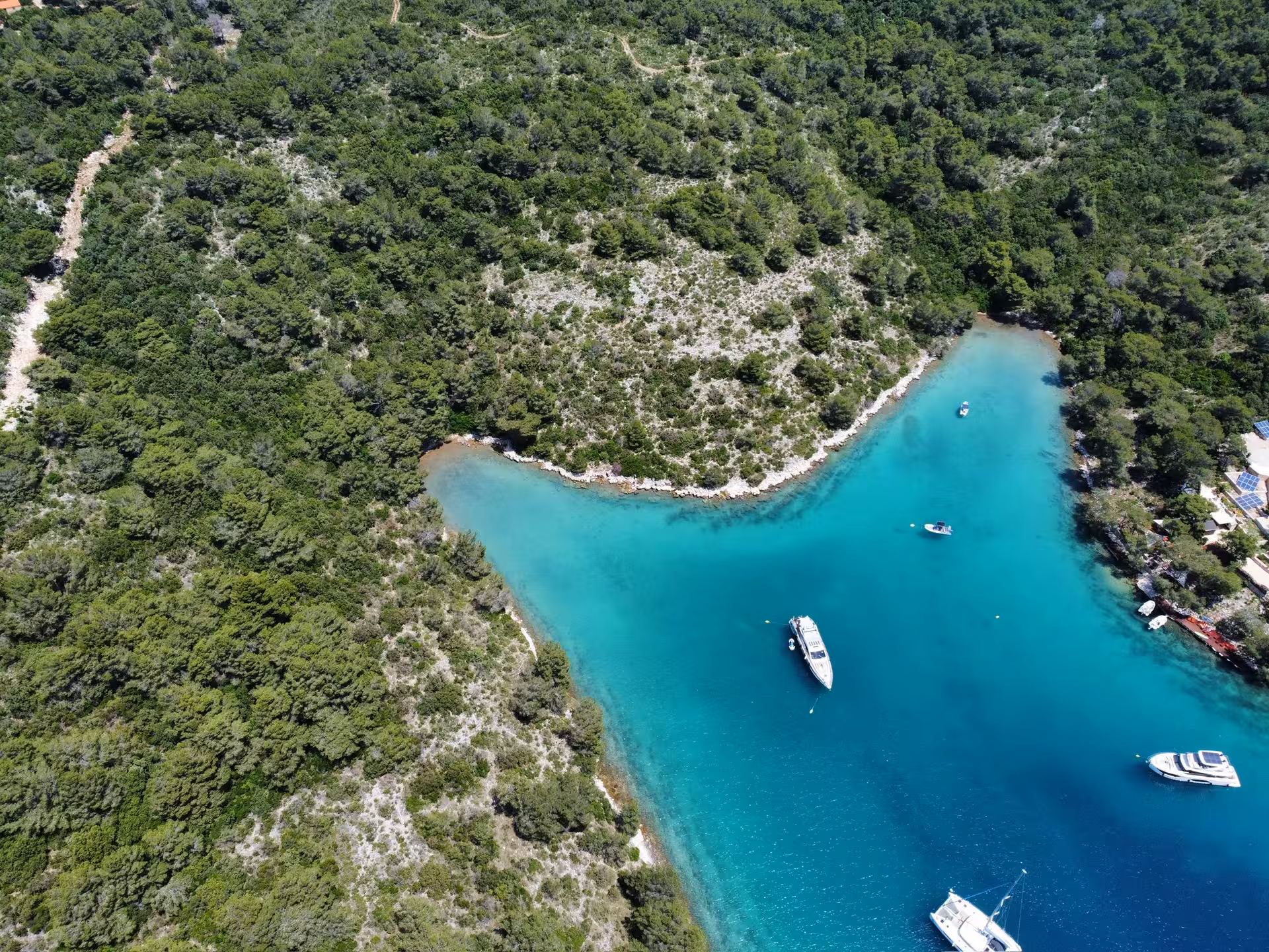 Aerial view of turquoise bay with anchored yachts and forested coastline on a scenic sailing adventure tour