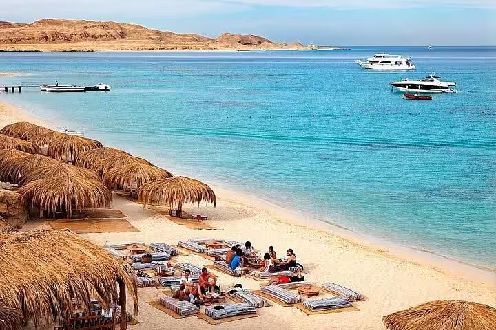 Ain El Sokhna Red Sea beach with straw umbrellas, sunbeds and boats, ideal day tour from Cairo, Egypt