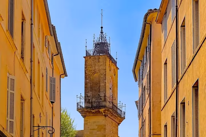 Clock tower framed by ochre buildings in Aix-en-Provence, scenic walk on Cézanne and winegrowers tour