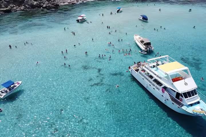 Aerial view of Akamas Blue Lagoon boat stop with swimmers in clear water on Paphos bus and boat tour