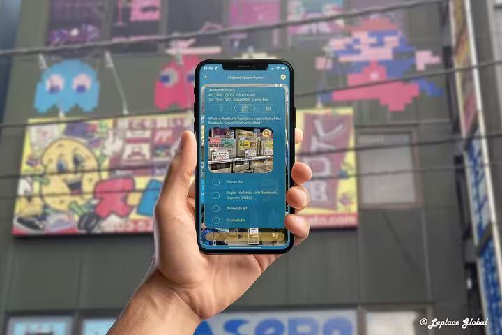Interactive gaming quiz on mobile app held up against colorful retro arcade mural in Akihabara Electric Town Tokyo