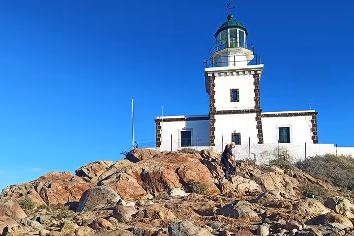 Akrotiri lighthouse on Santorini cliff under blue sky, highlight of a private 3-day tour with transfers