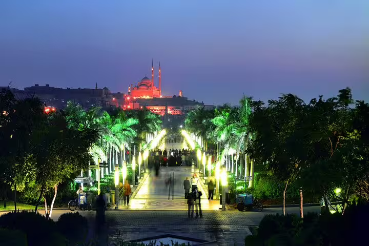 Night view of Al Azhar Park promenade with lit palms and Cairo mosque skyline, Al-Mu'izz Street tour dinner