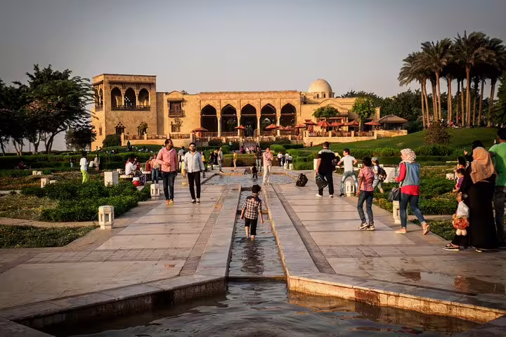 Visitors stroll Al Azhar Park gardens at sunset, a highlight of Al-Mu'izz Street tour with dinner in Cairo