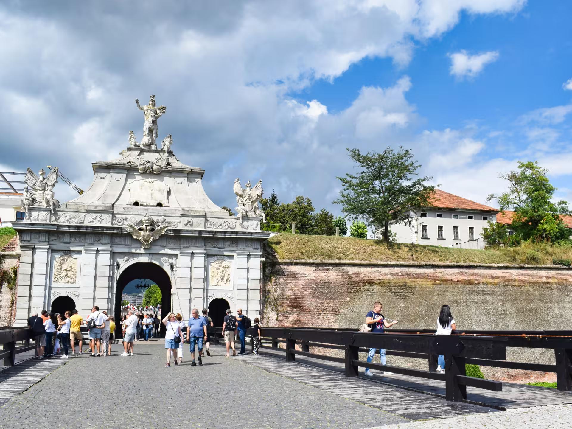 Visitors exploring the ornate Baroque gate of Alba Carolina Fortress on a Transylvania castle tour