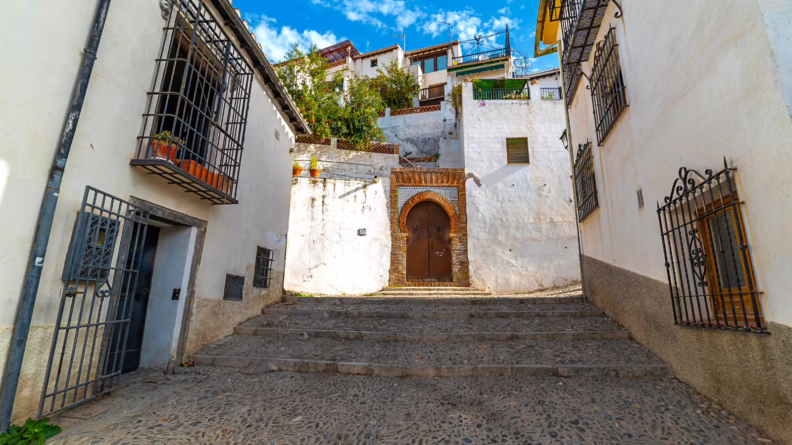 Cobbled Albaicín street in Granada with whitewashed houses, seen on Alhambra and Granada private tour with hotel pickup