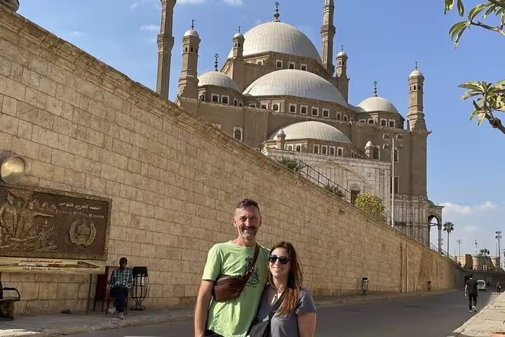 Travelers pose by Alexandria Citadel walls with Mohamed Ali Mosque domes on Alexandria port shore tour