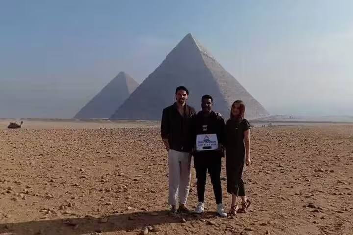 Private tour from Alexandria Port to Giza Pyramids with guide and guests posing on desert plateau