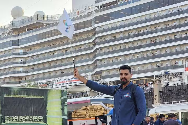 Tour guide holding flag at Alexandria Port cruise pickup for private Giza Pyramids, Sakkara and camel ride tour