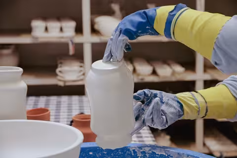 Worker glazing a ceramic bottle by hand in an Algarve factory, part of the immersive Cans & Bottles production tour