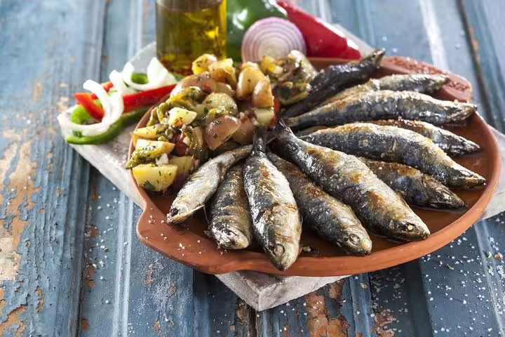 Grilled sardines with seasoned potatoes, a traditional Algarve dish, served on a rustic plate for a Portuguese culinary experience.