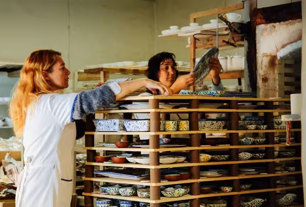 Artisans loading colorful hand-painted Algarve ceramic cans and bottles into a kiln during a pottery workshop visit