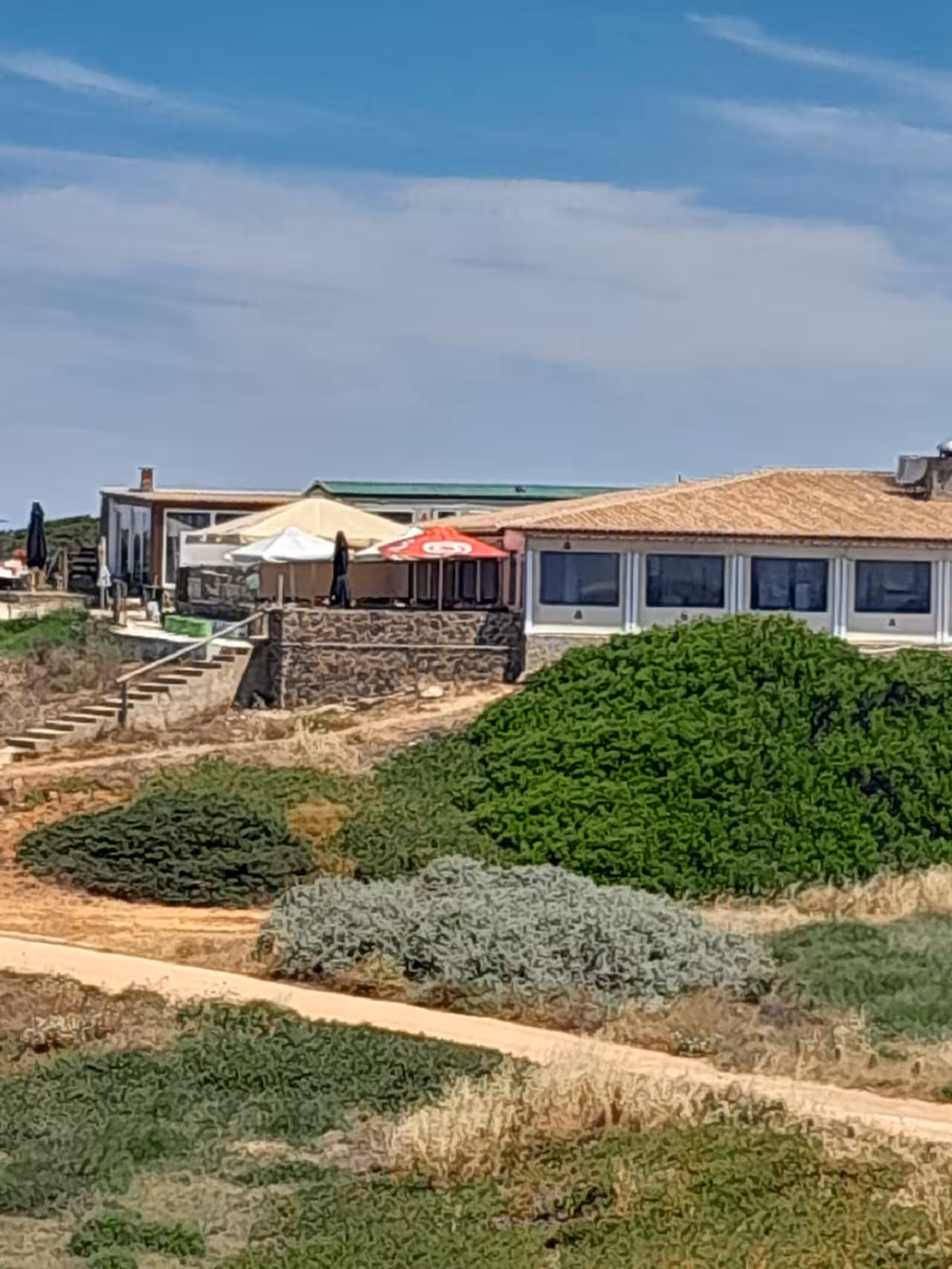 Clifftop seaside restaurant with sun umbrellas and coastal walking trail on the Algarve West Coast full day tour