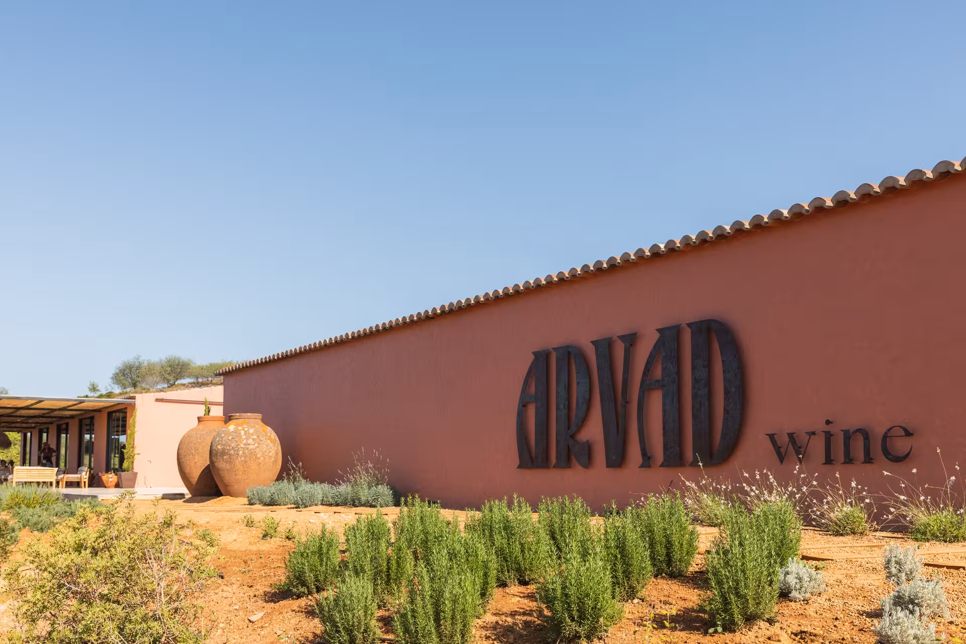 Arvad Wine estate in the Algarve with terracotta walls, rustic amphora jars and herb garden under clear blue skies