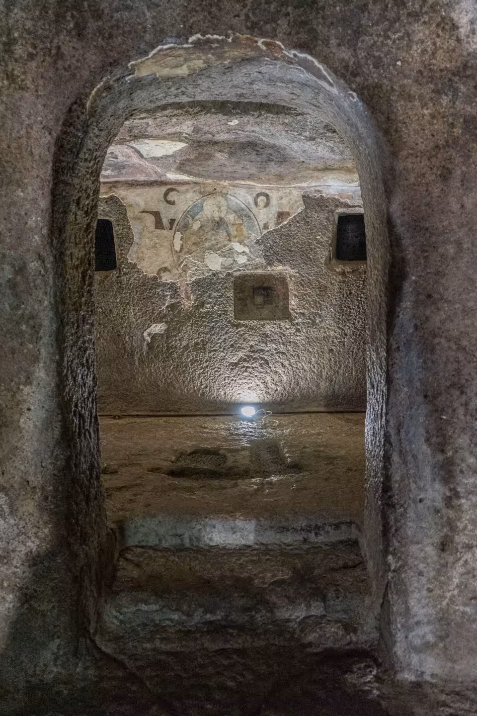Step into Alghero's mysterious underground chambers with ancient carvings illuminated by soft lighting.