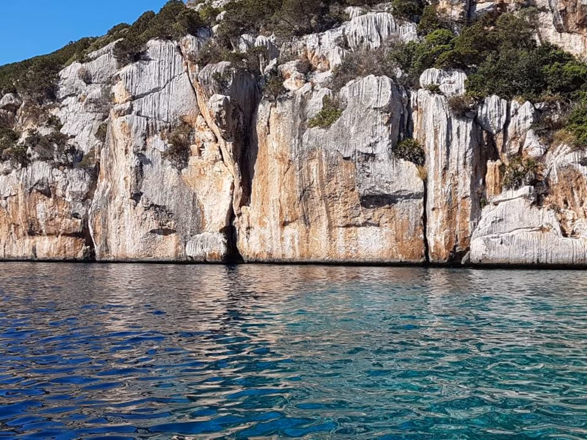 Majestic Capo Caccia cliffs reflecting in the clear turquoise waters of Alghero, perfect for a snorkelling adventure.