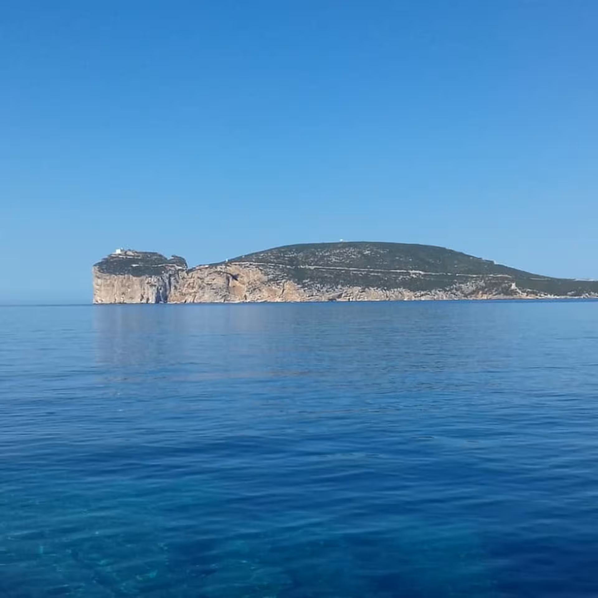 Vast blue seascape with Capo Caccia cliff formations, ideal setting for snorkelling tours in Alghero, Sardinia.