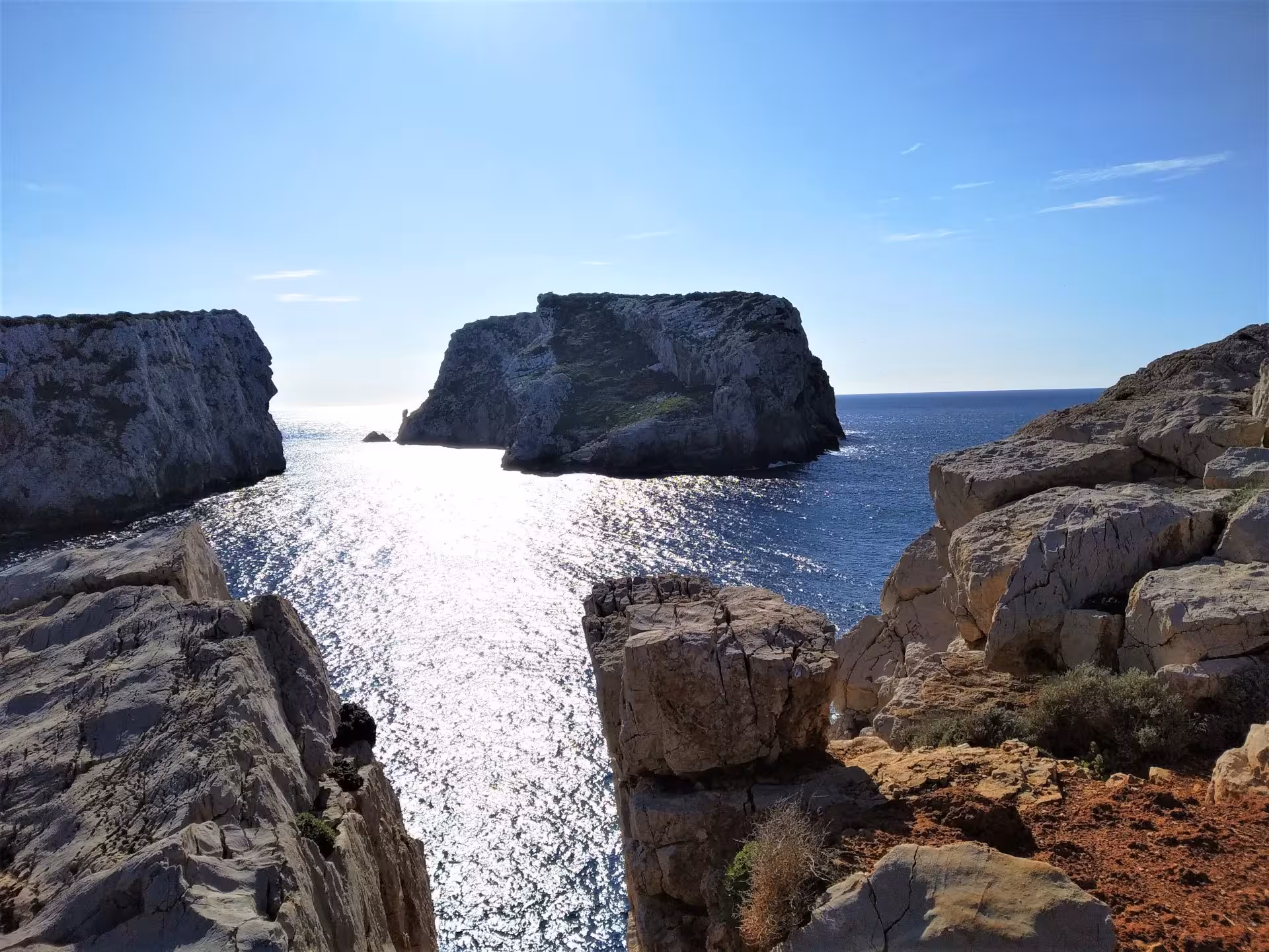 Breathtaking view of rocky cliffs and sparkling sea in Porto Conte Park, Alghero, perfect for a peaceful golf cart tour.