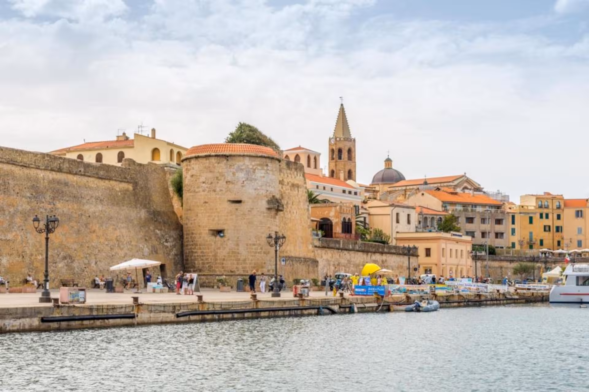 Alghero waterfront with historic walls and vibrant cityscape, ideal for sightseeing and photography.