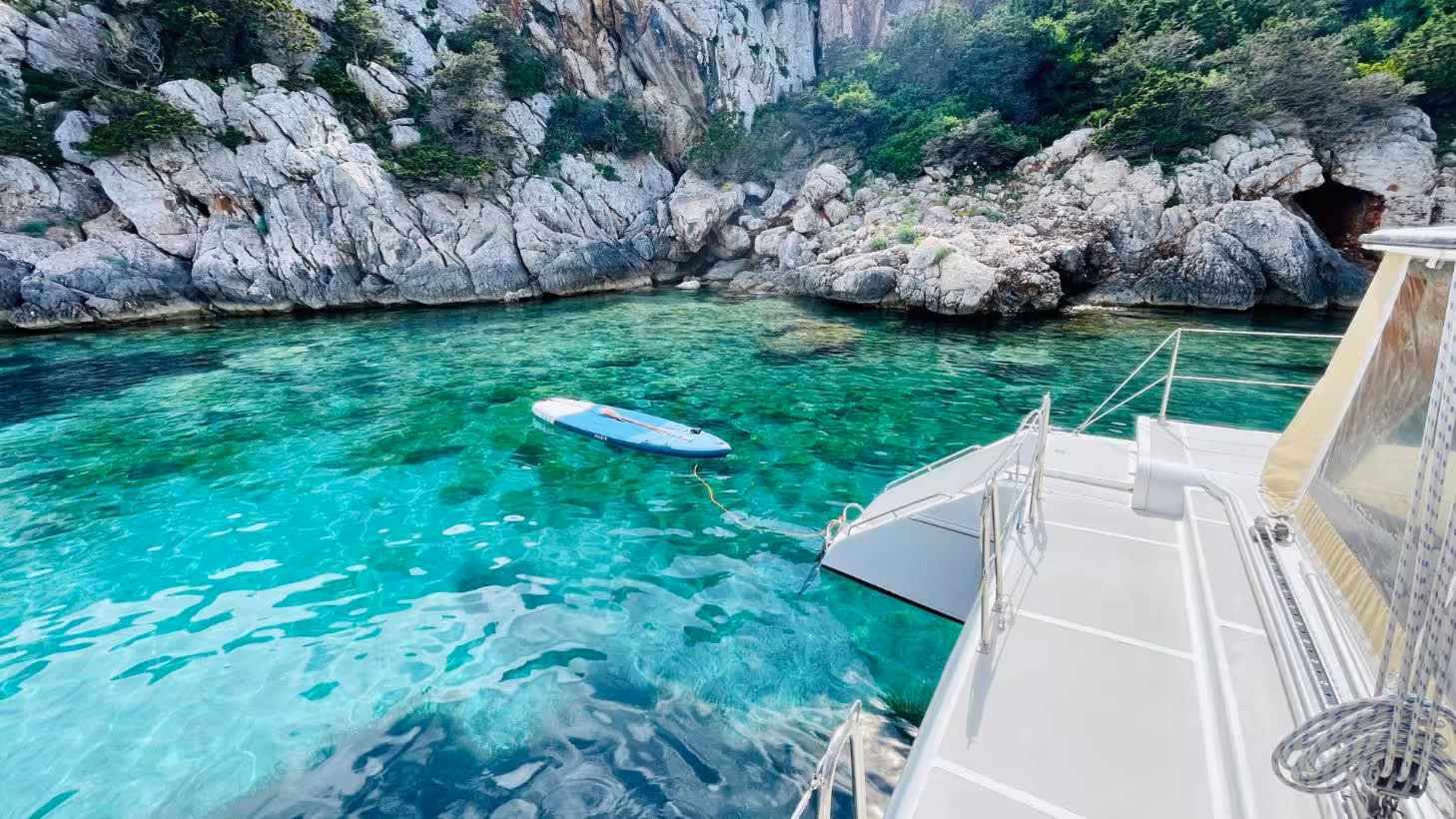 Scenic view from a catamaran in Porto Conte Park with crystal-clear waters and rocky cliffs near Alghero.