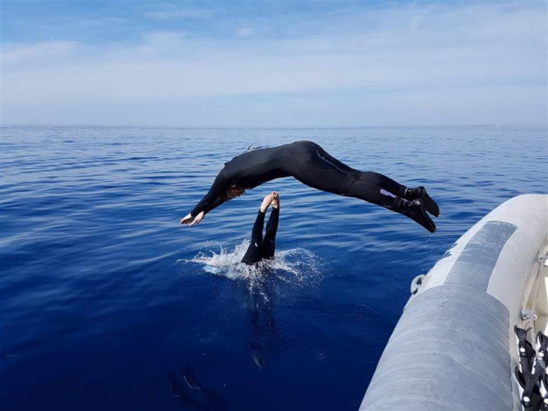 Diver mid-air above the clear blue sea near Capo Caccia, Alghero, showcasing thrilling snorkeling adventures.