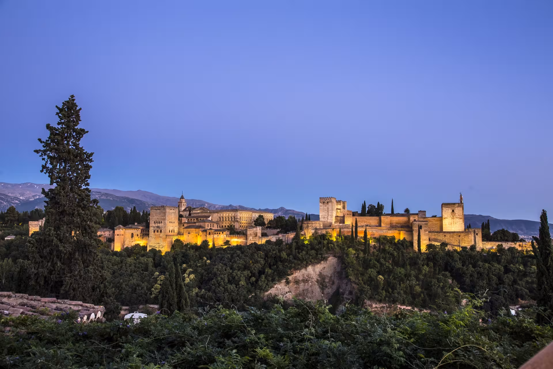 Stunning evening view of the Alhambra fortress illuminated against the twilight sky, showcasing its architectural grandeur.