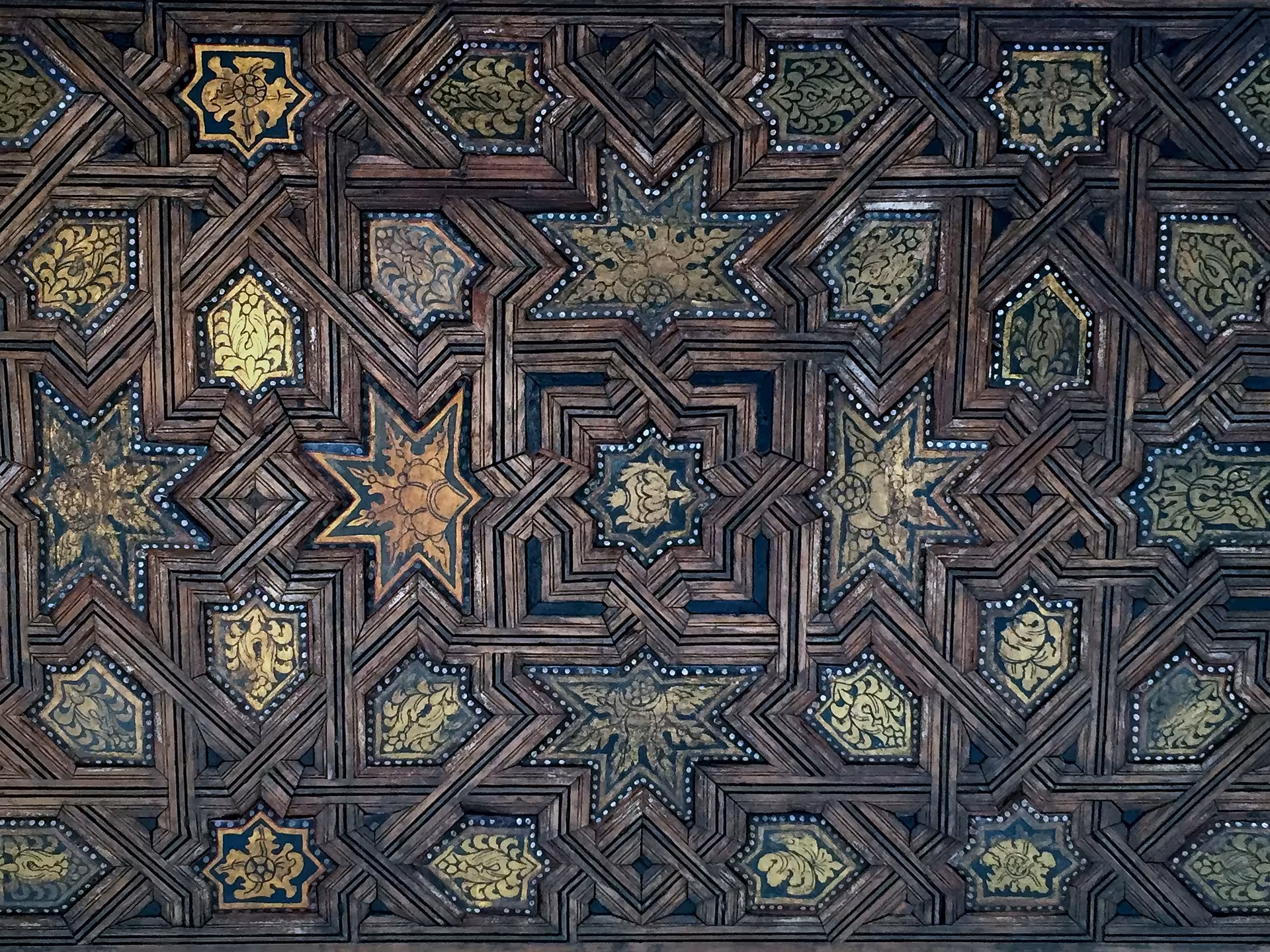 Intricate star-patterned wooden ceiling in the Alhambra's Nasrid Palaces, showcasing Islamic art and design.