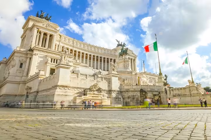 The majestic Altare della Patria in Rome, featuring Italian flags, part of the Full Day Shore Excursion from Civitavecchia.