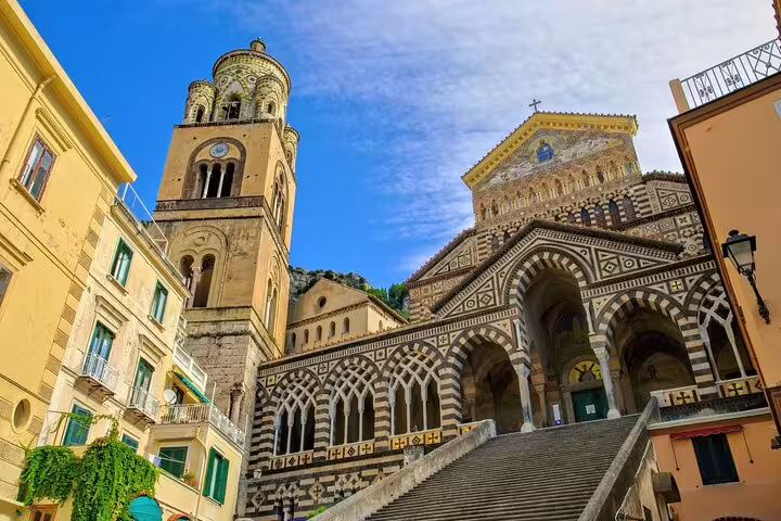 Grand staircase leading to Amalfi Cathedral and bell tower under blue sky, a highlight of Amalfi town private walking tours