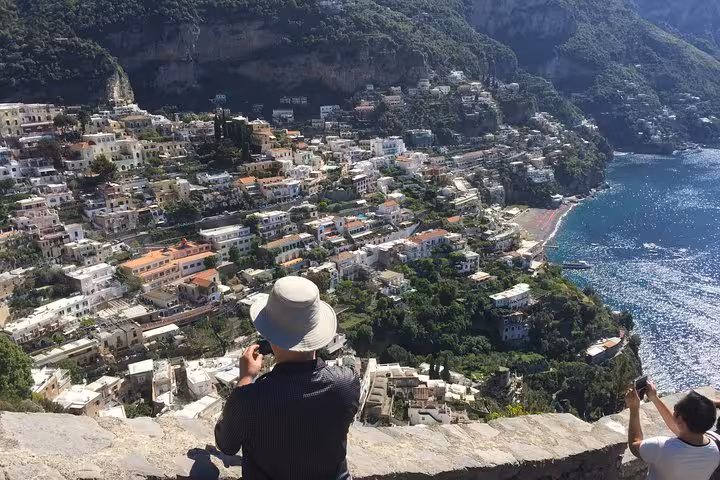 Tourists capturing breathtaking views of Positano's picturesque hillside homes and azure coastline on the Amalfi Coast.