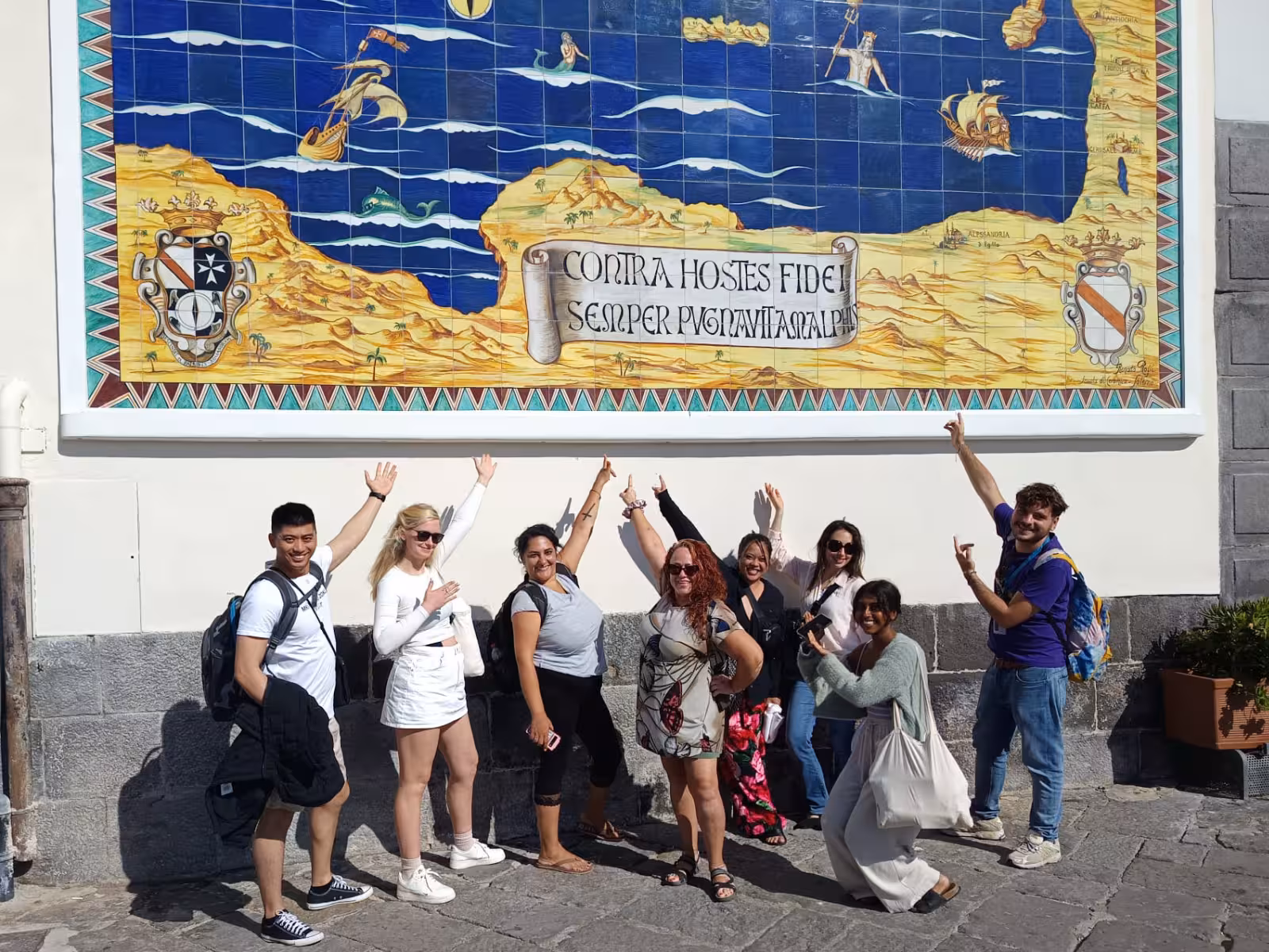 Tour group posing in front of a historic tile mural on the Amalfi Coast, highlighting cultural heritage.