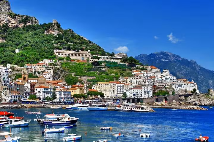 Scenic view of Amalfi coast with colorful hillside buildings and boats in the vibrant blue sea.
