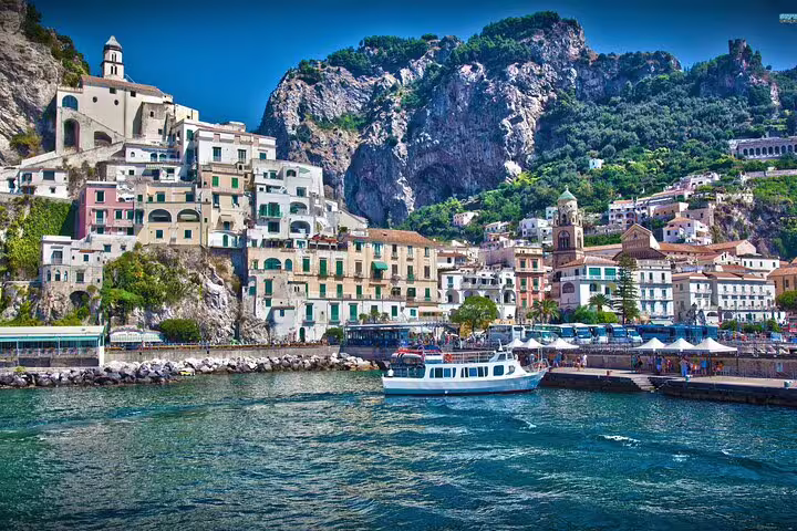 Amalfi town waterfront with boat and cliffside houses, luxury private Amalfi Coast day trip from Naples