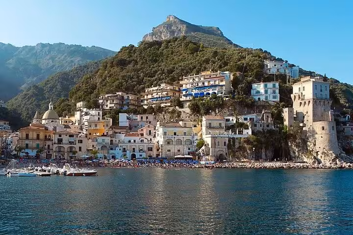 Scenic view of Amalfi town with mountain backdrop, featuring charming coastal architecture and azure waters.