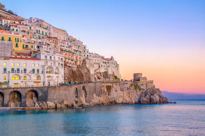 Colorful Amalfi Town houses perched on seaside cliffs at sunset, viewed from the water on a personalized walking tour